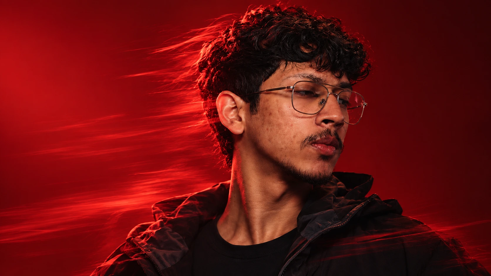 MD Sadaf in dramatic red light, wearing glasses and a black jacket